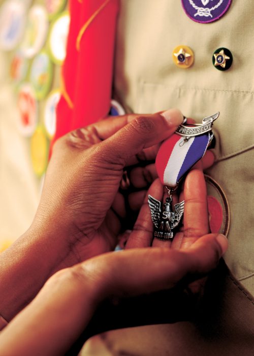 hands holding eagle medal pinned on a uniform shirt - eagle award - eagle scout